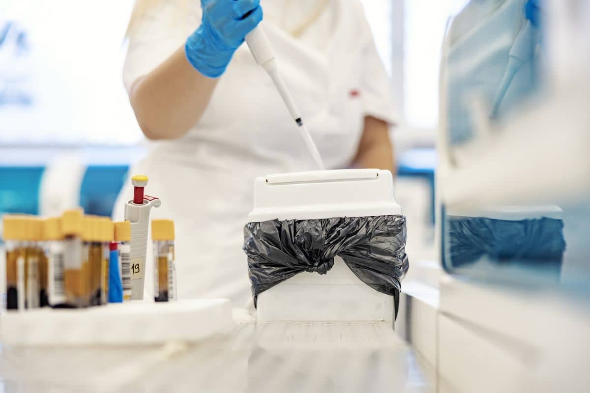 a lab team member disposing of medical waste in a container