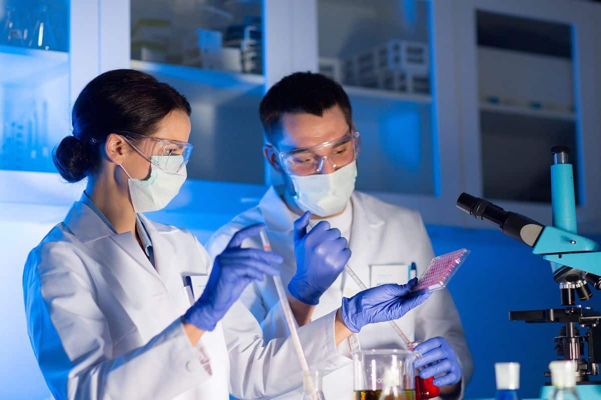 a female and male scientist using a pipette and flasks in a clinical laboratory