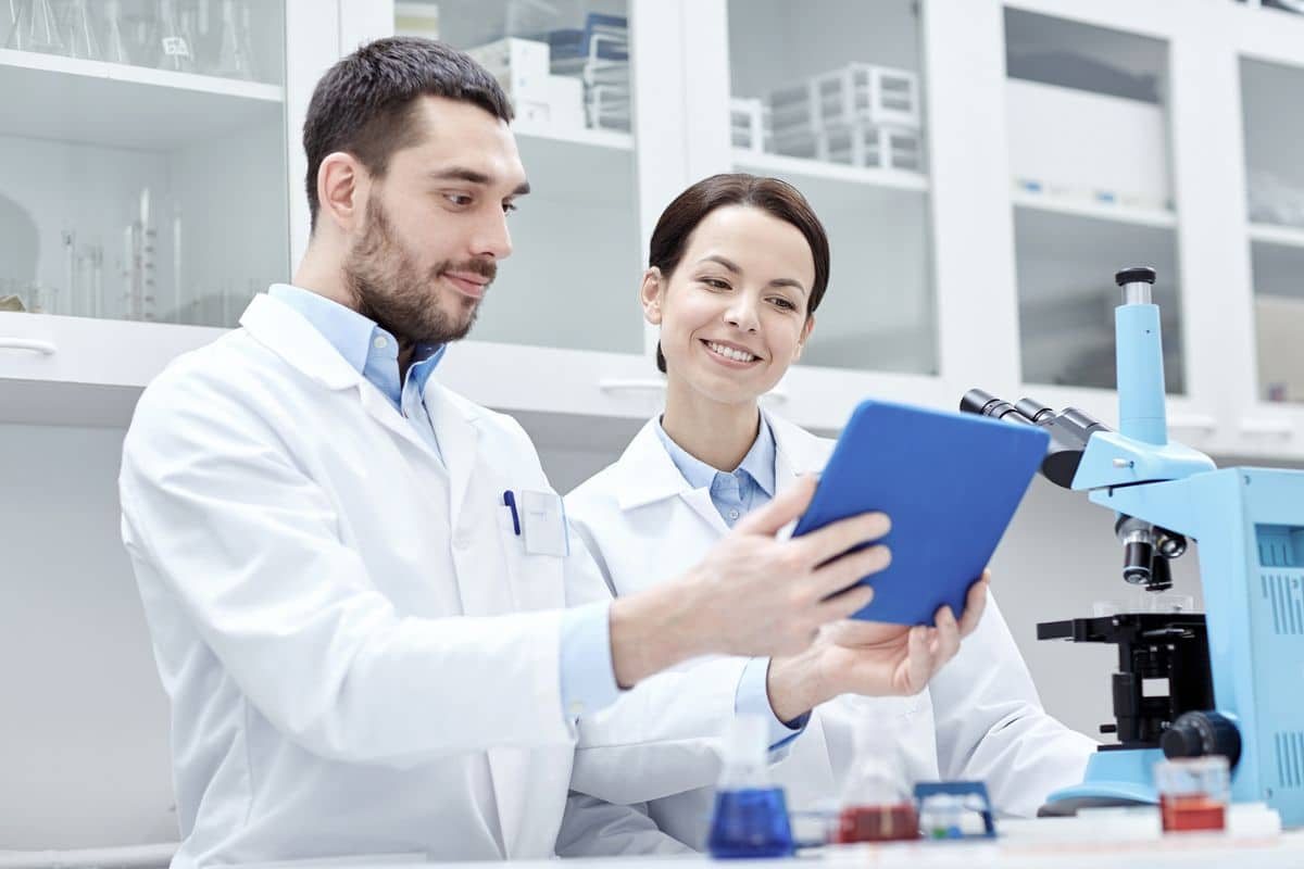 a male and a female in lab coats standing in a clinical research lab